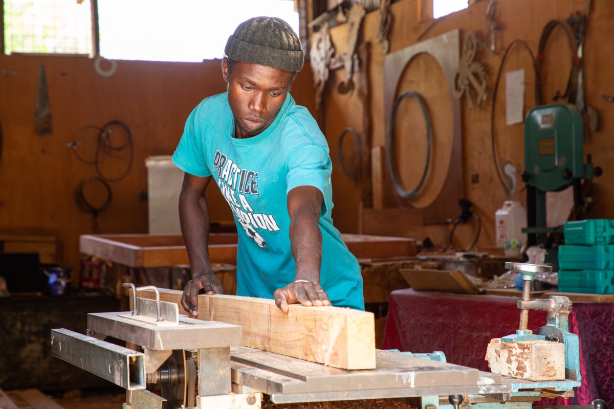 A carpentry trainee planing a timber board in the workshop